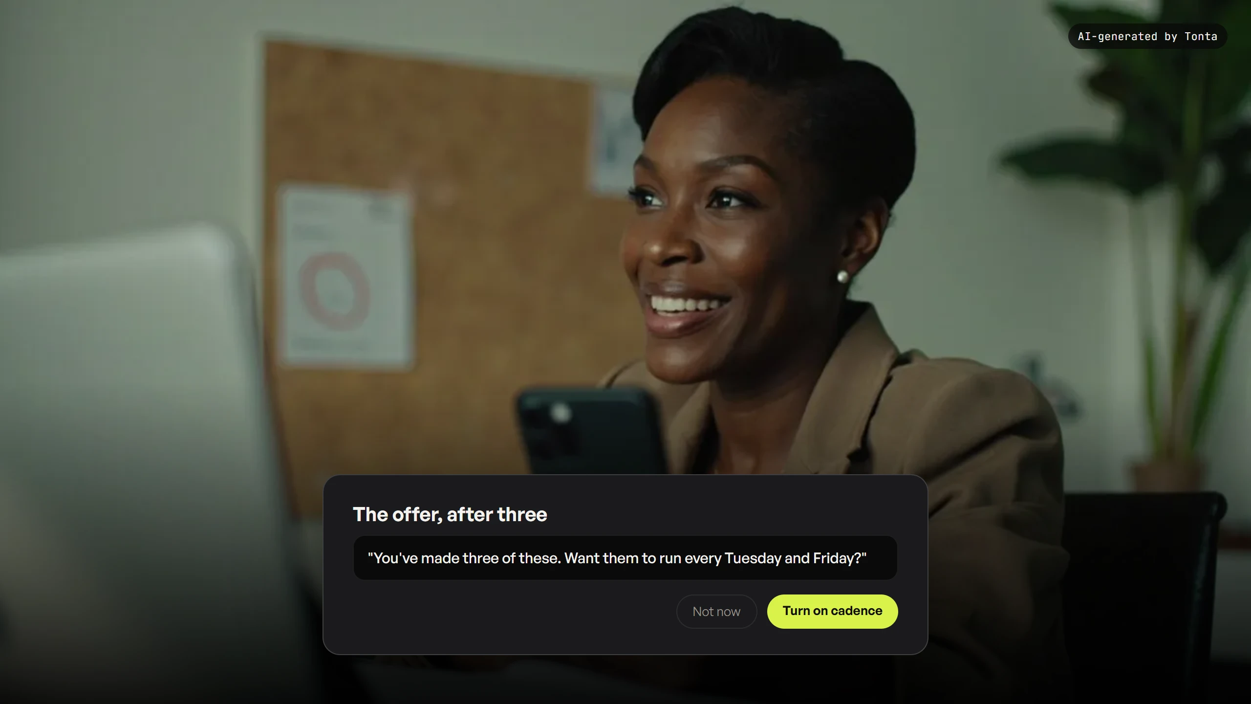 A fictional creator looking at her phone with a pinboard calendar visible behind her, pleased expression.